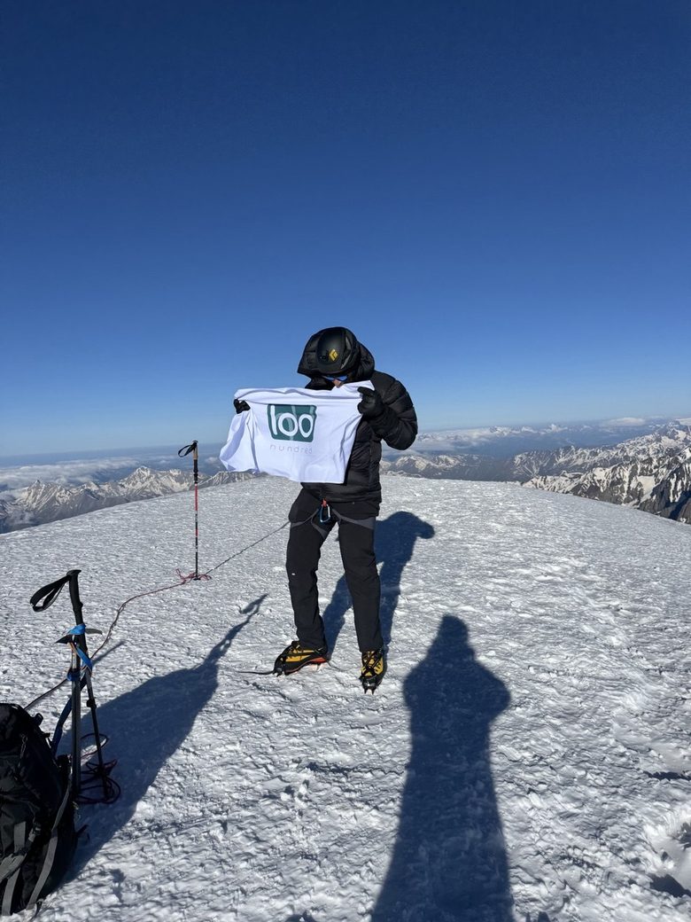 Narek Abgaryan on the summit of Mount Kazbek holding the Hundred flag